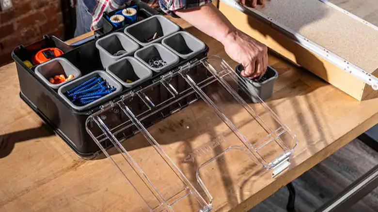 A man putting parts and tools into a Husky organizer.