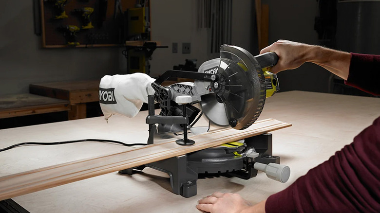 A man using a Ryobi miter saw to cut wood.