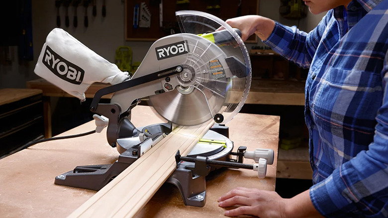 A man cutting a piece of wood with a Ryobi Miter Saw.