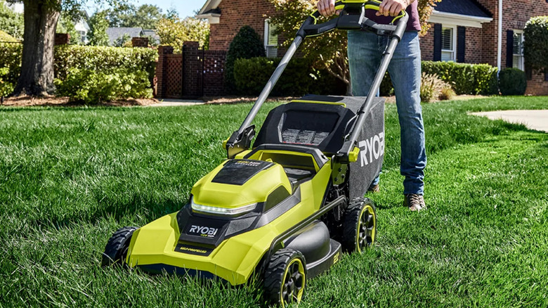 A man pushing a 21-inch Ryobi electric lawnmower.