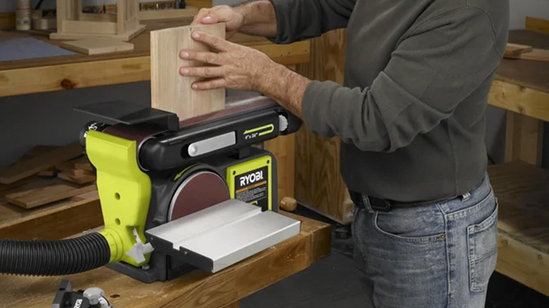 A man using a Ryobi belt and disc sander duo on a piece of wood.