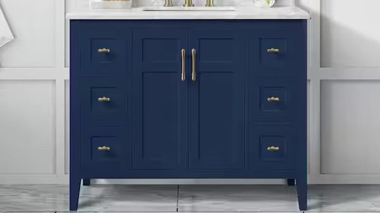A blue and white bathroom sink and cabinet area with gold handles.