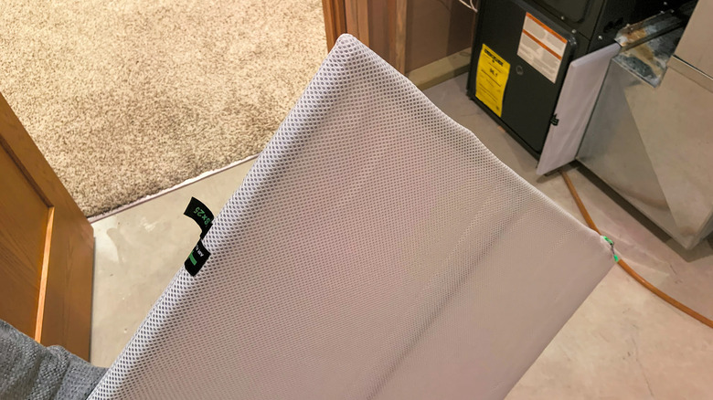 A person holding an HVAC filter near a furnace.