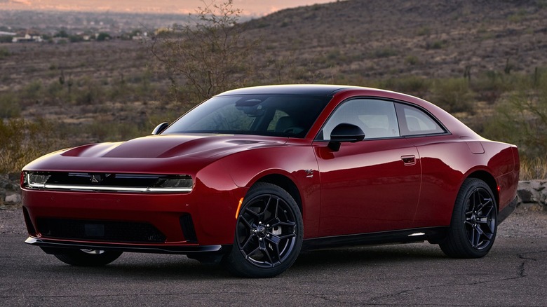 A red All-new Dodge Charger Daytona R/T  is parked against a desert backdrop at sunset.