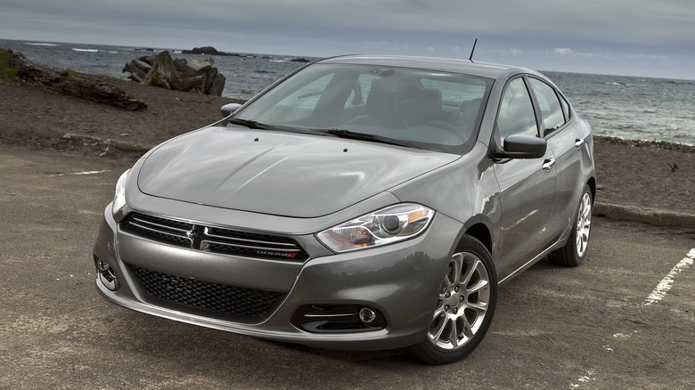 A 2013 gray Dodge Dart Limited is parked by a beach under a cloudy sky.