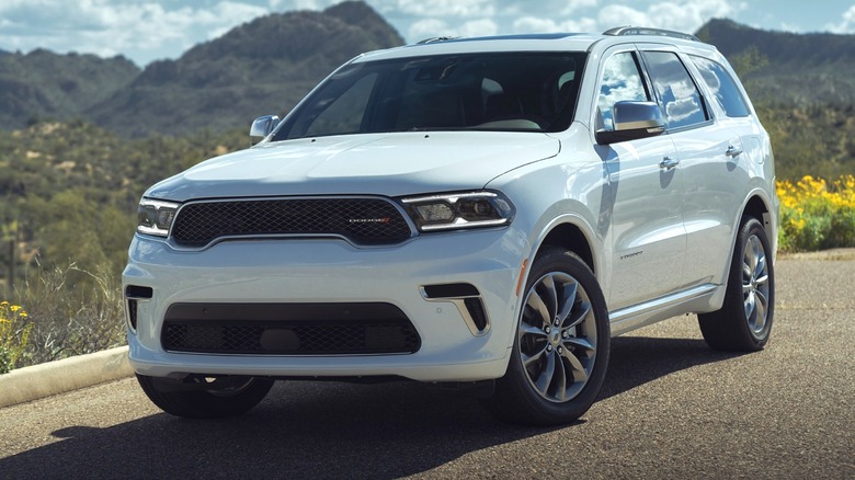A white 2024 Dodge Durango Citadel SUV is parked on a scenic road with mountains in the background.