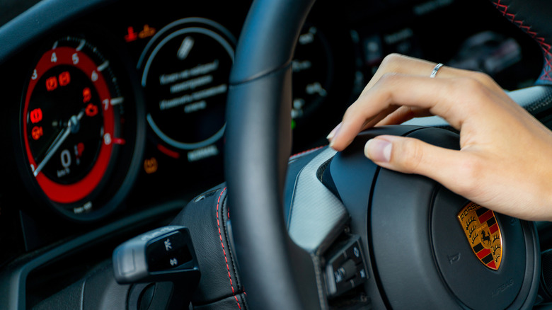 A person in a Porsche with their hand on the horn