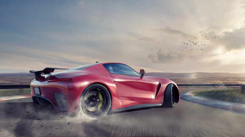 A sports car drifting on a race track with smoke coming out from the rear tire