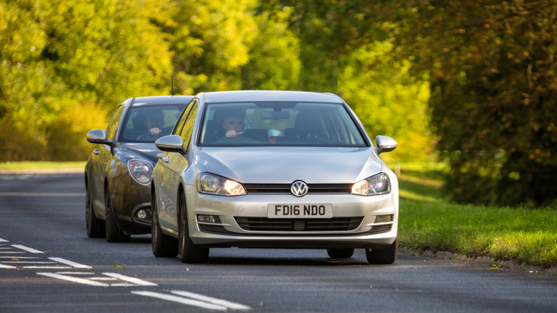 A silver Golf being tailgated on a road