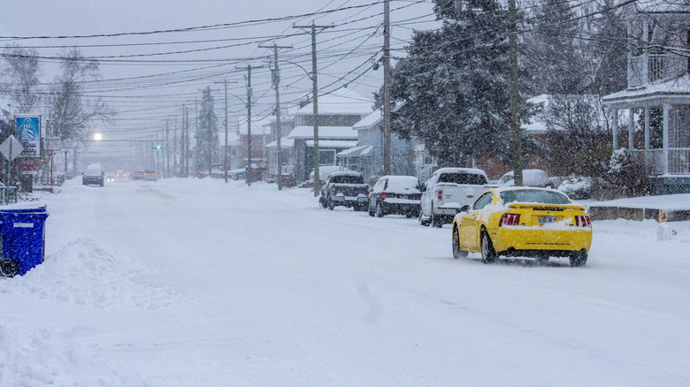 A yellow Ford Mustang driving in a blizzard
