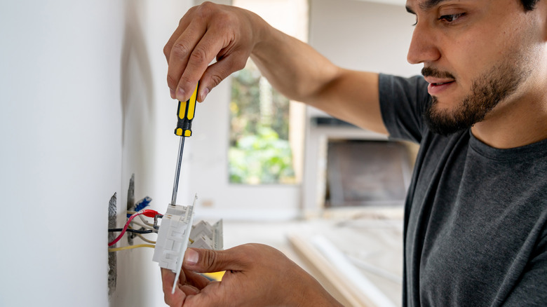 A person installing a power socket inside a house