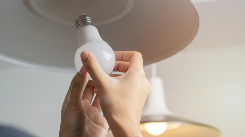 A woman changing a light bulb