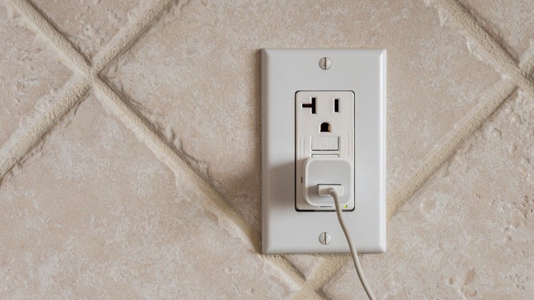A charging adapter plugged into a GFCI wall outlet