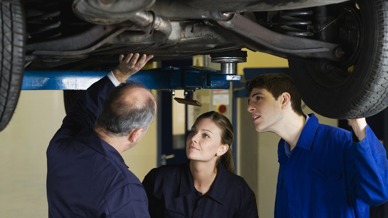 Mechanic examining car with couple
