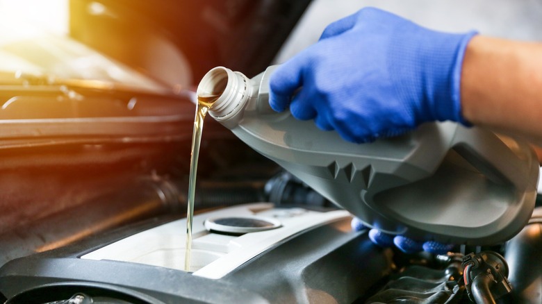 Technician pouring oil into engine