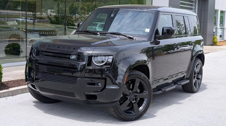 Black 2026 Land Rover Defender 110 V8 parked in front of a dealership window
