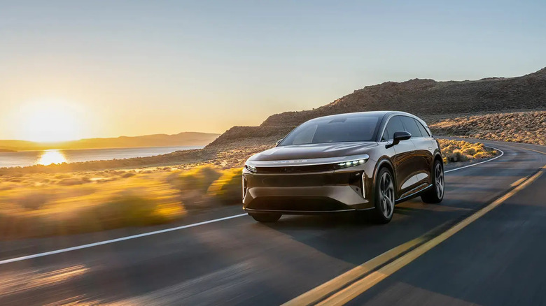 A 2026 Lucid Gravity Grand Touring driving by a body of water.
