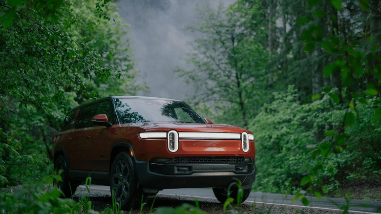 An orange 2026 Rivian R1S parked in nature.