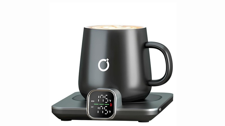 A coffee mug on top of a warmer showing temperature levels on the display