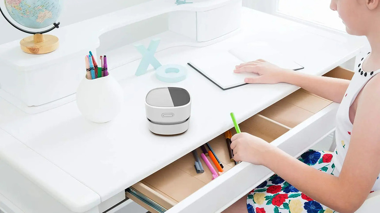 Person arranging a white desk with the Odistar vacuum on top of it