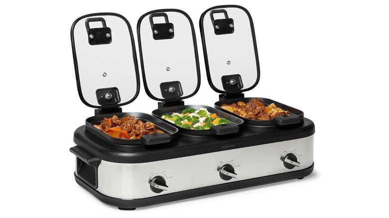 Stock photo of three slow cookers with lids removed showing food inside
