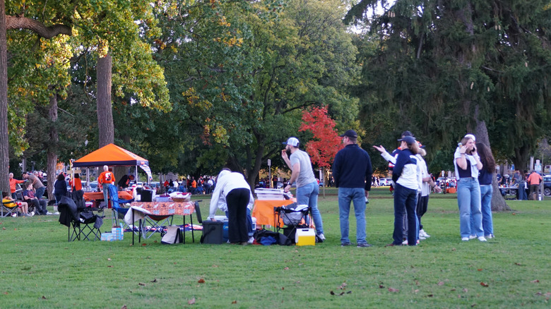 Group of people in a public outdoor space with food tables and tents