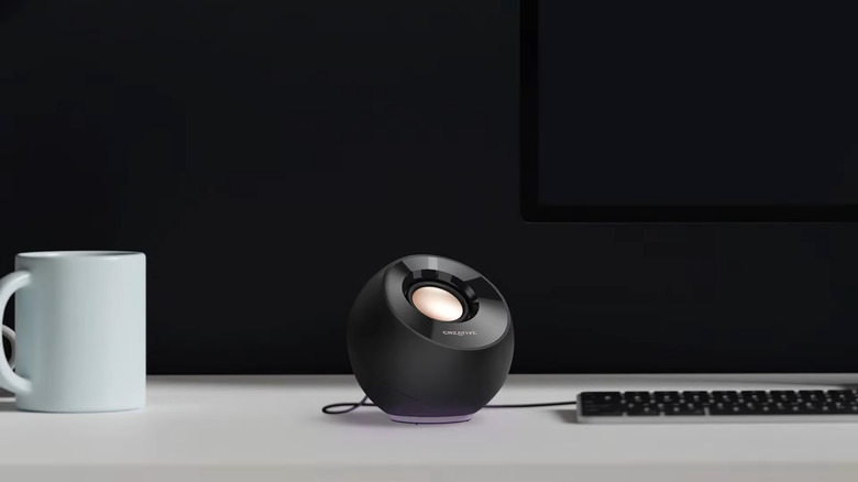 A Creative Pebble SE set on a white desk against a black wall.