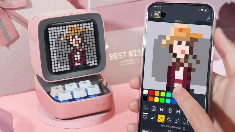 A Divoom Ditoo Pro on a desktop with a person using a phone with the accompanying app
