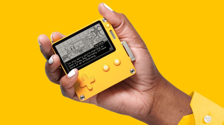 A person holding Playdate gaming console against a yellow background
