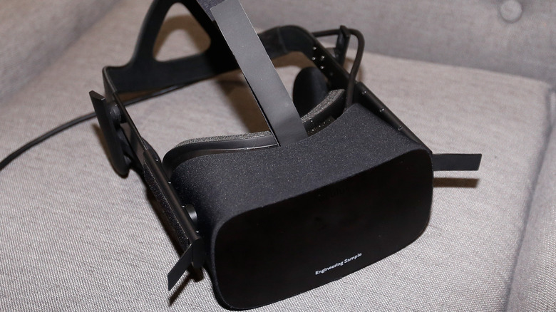 Black Oculus virtual reality headset on a gray couch.