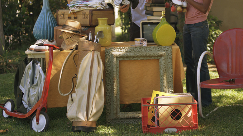 People browsing household items and gadgets at a yard sale.