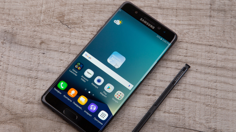 Samsung Galaxy Note 7 smartphone lying next to its stylus on a wooden table.