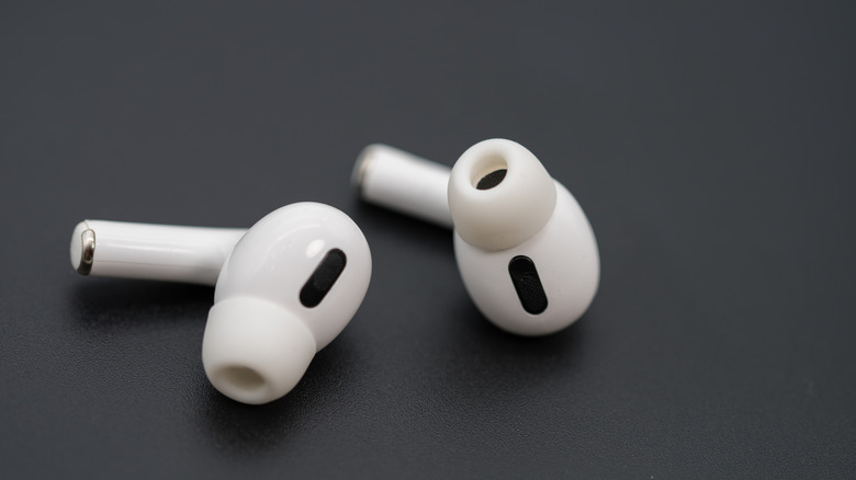 Pair of white Apple AirPods Pro lying on a gray surface.