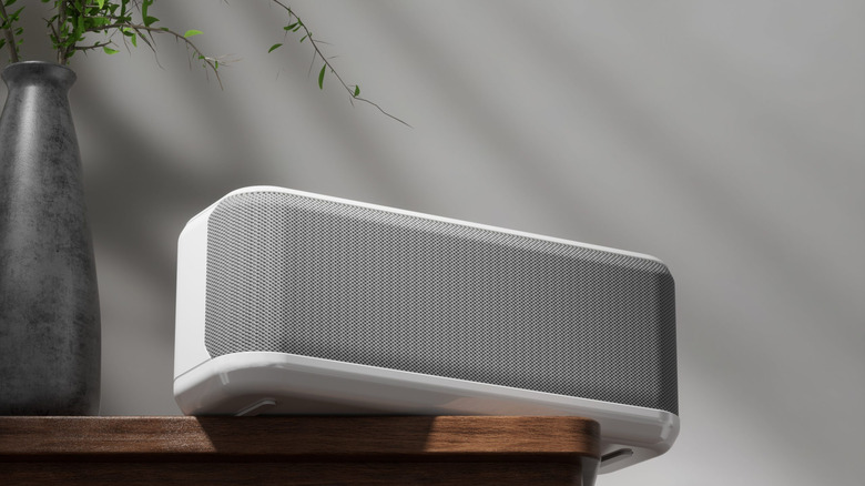 A white OnLyee white noise machine resting on a wooden table beside a plant vase