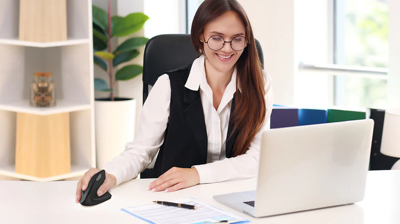 A woman scrolling on her computer with a black Tecknet ergonomic mouse