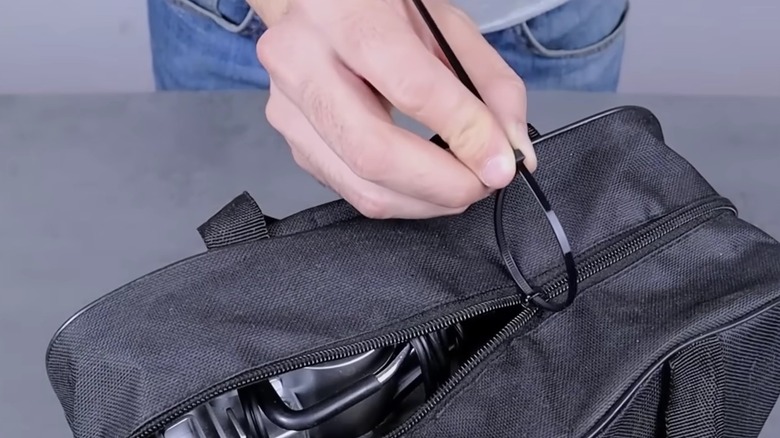 Person attaching zip tie to a broken zipper