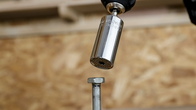 Power drill with universal socket preparing to fasten screw