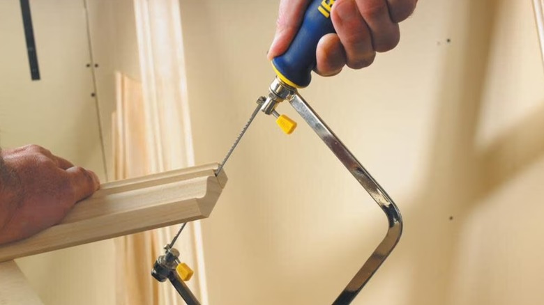 Worker cutting molding with a coping saw