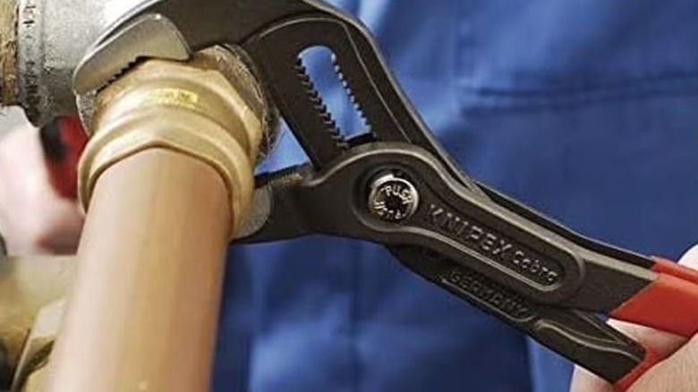 Worker grabbing pipe with Knipex Cobra pliers