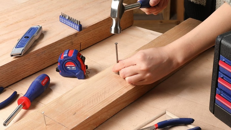 Worker hammering a nail into lumber while using a WorkPro kit