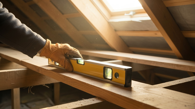 A worker using a level during an attic installation