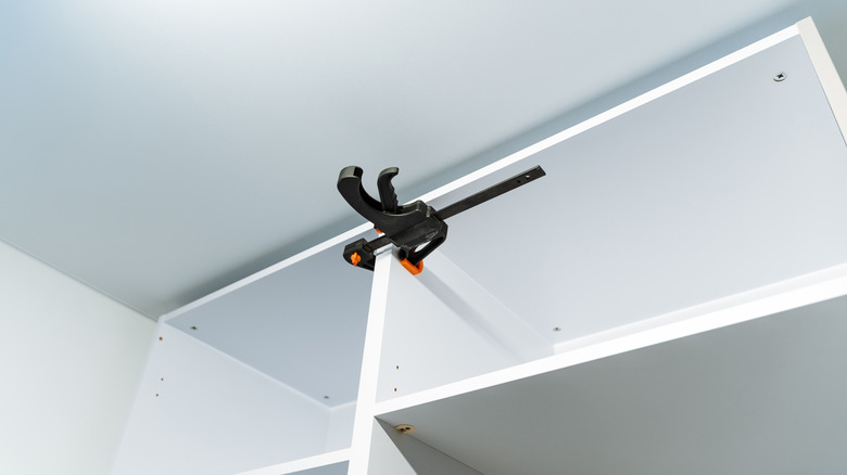 A bar clamp being used to hold cabinet boxes in place