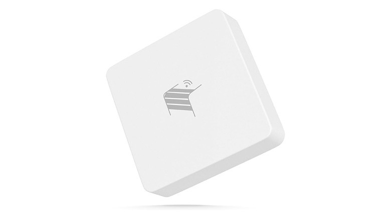 A square, light gray garage door sensor with a dark gray logo in its center, set against a white background.