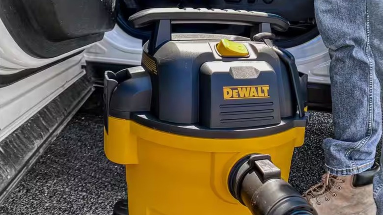 A DeWalt Shop Vac being used to clean the interior of a vehicle