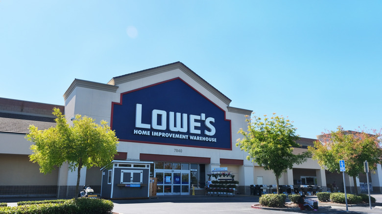 A Lowe's storefront on a clear day, flanked by well-landscaped trees in a parking lot