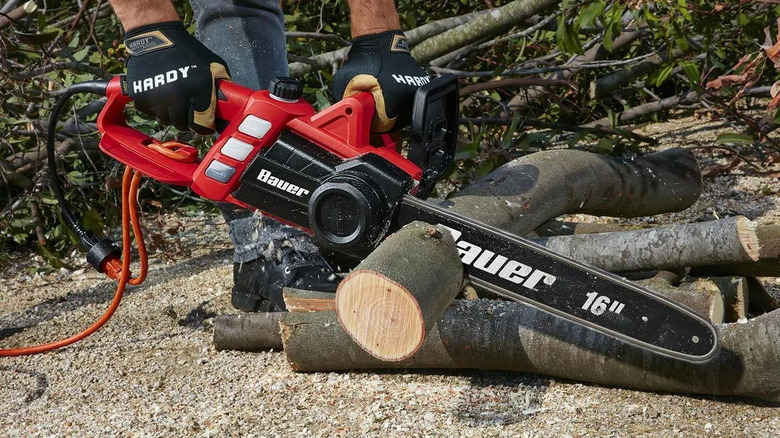 Bauer corded chainsaw cutting wooden logs.