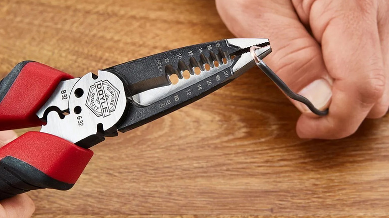 A man stripping a wire with pliers