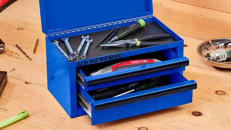 A blue U.S. General mini toolbox with various tools on a workbench.