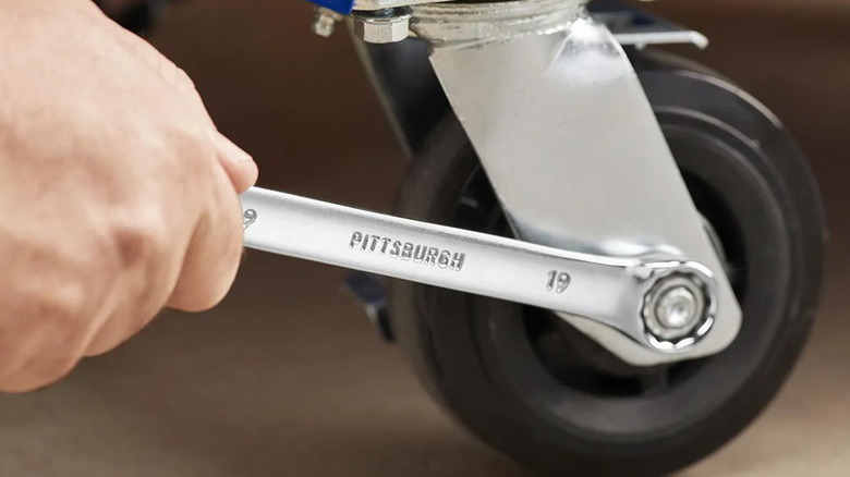 A person using a Pittsburgh wrench to tighten a wheel