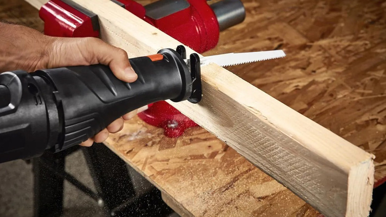 A person cutting a piece of wood with a Warrior reciprocating saw